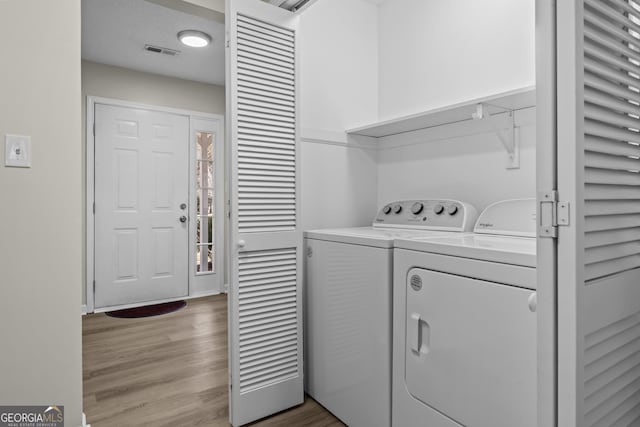 clothes washing area with independent washer and dryer and light hardwood / wood-style floors