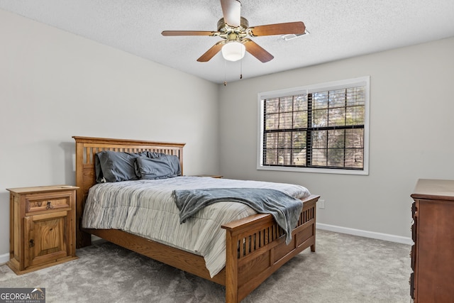 carpeted bedroom featuring ceiling fan and a textured ceiling