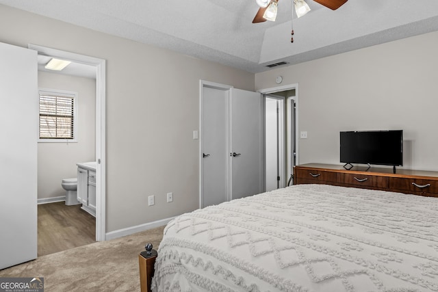 carpeted bedroom with ceiling fan, ensuite bathroom, and a textured ceiling