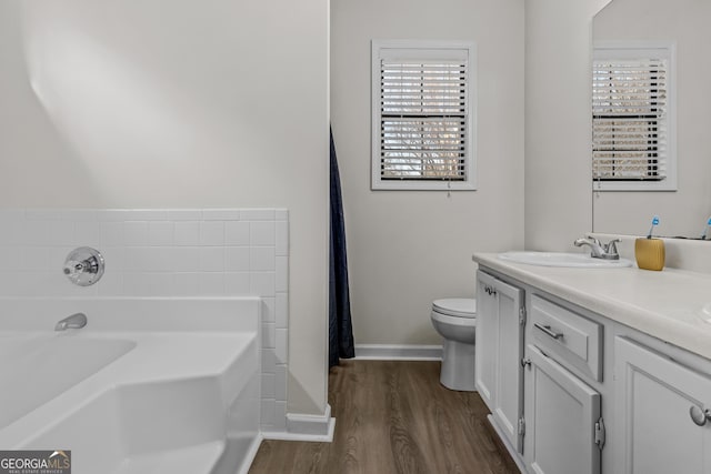 bathroom featuring vanity, hardwood / wood-style floors, toilet, and a bathing tub