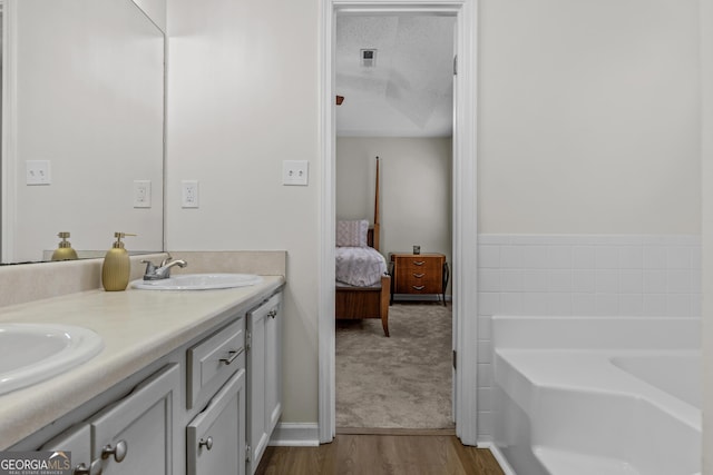 bathroom featuring hardwood / wood-style flooring, vanity, a bathing tub, and a textured ceiling