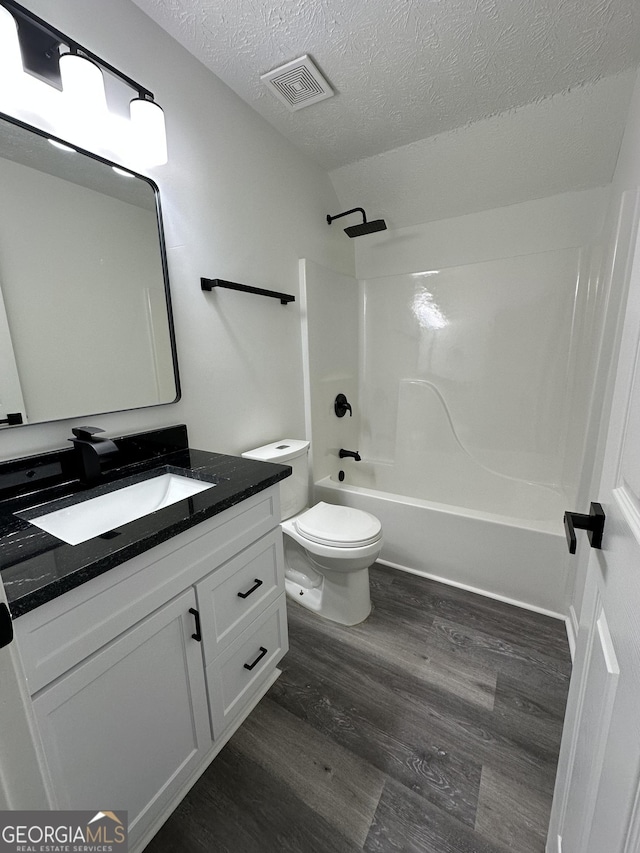 full bathroom with toilet, a textured ceiling, vanity, shower / bath combination, and hardwood / wood-style floors