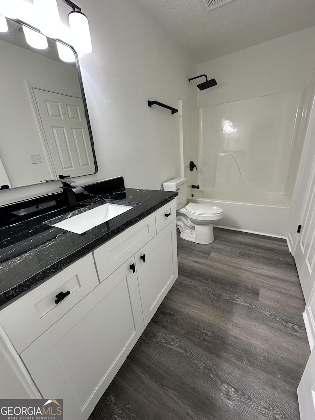 full bathroom with wood-type flooring, vanity, toilet, bathing tub / shower combination, and a textured ceiling