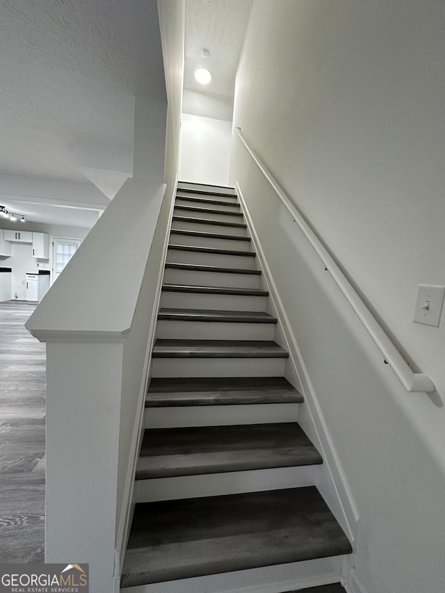 staircase featuring wood-type flooring and a textured ceiling