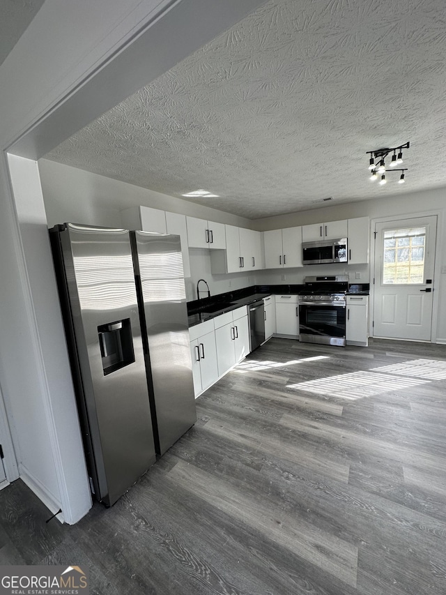 kitchen featuring white cabinetry, dark hardwood / wood-style flooring, stainless steel appliances, and a textured ceiling