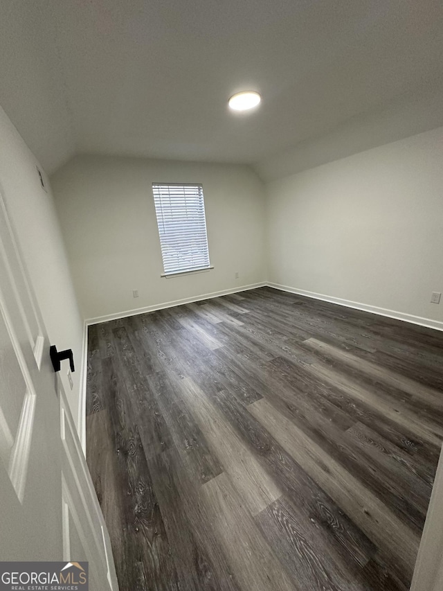 unfurnished room with dark wood-type flooring and lofted ceiling