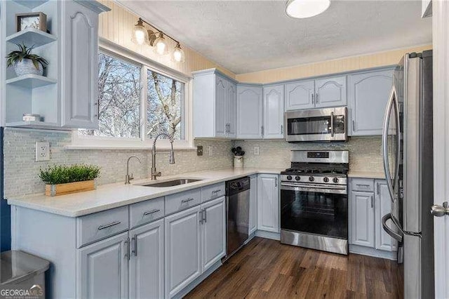 kitchen with sink, tasteful backsplash, dark hardwood / wood-style flooring, gray cabinets, and stainless steel appliances