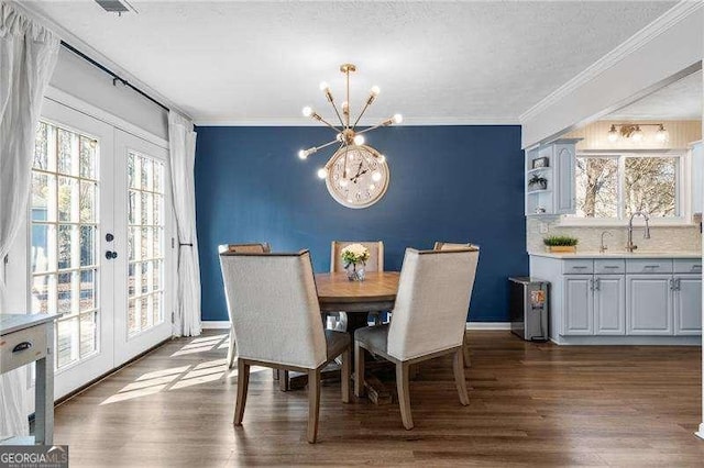 dining area featuring crown molding, dark wood-type flooring, french doors, and a chandelier