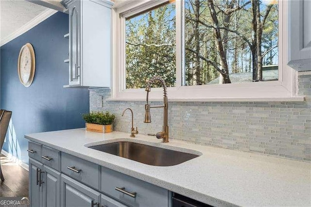 kitchen featuring ornamental molding, sink, gray cabinetry, and decorative backsplash