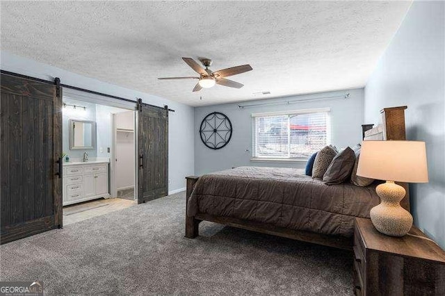 bedroom with sink, ceiling fan, a textured ceiling, light carpet, and a barn door