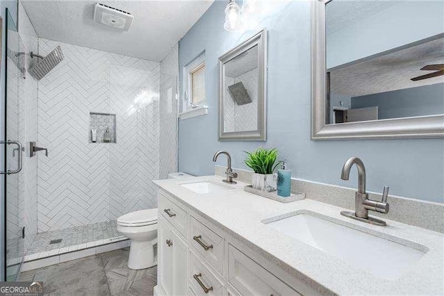 bathroom featuring vanity, a textured ceiling, a shower with door, and toilet