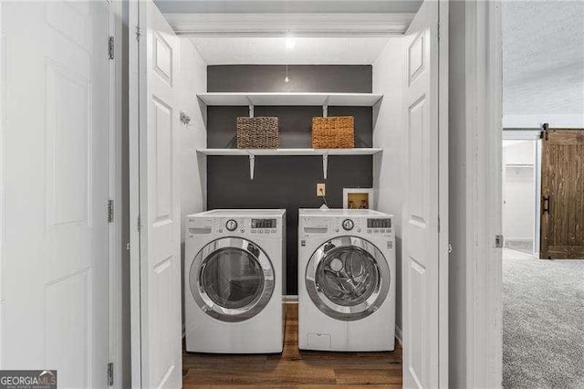 laundry room with washing machine and clothes dryer, a barn door, and dark carpet