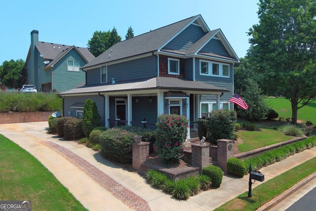 10 Plum Blossom Ln, Hampton, GA 30228 - view of front facade featuring covered porch, metal roof, and a front lawn
