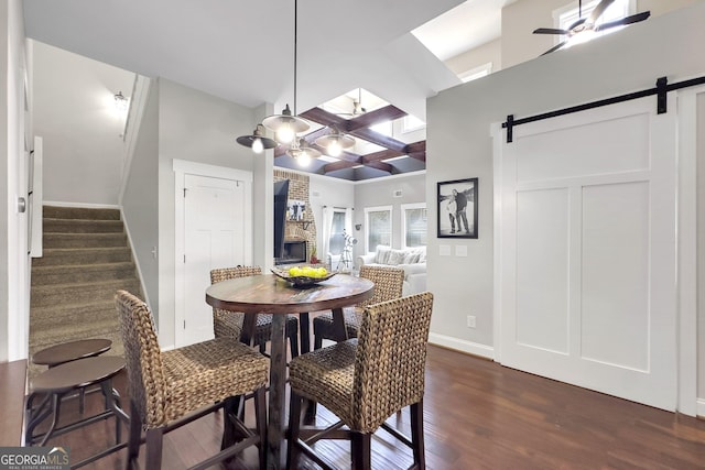 dining room with ceiling fan, a barn door, and dark hardwood / wood-style flooring