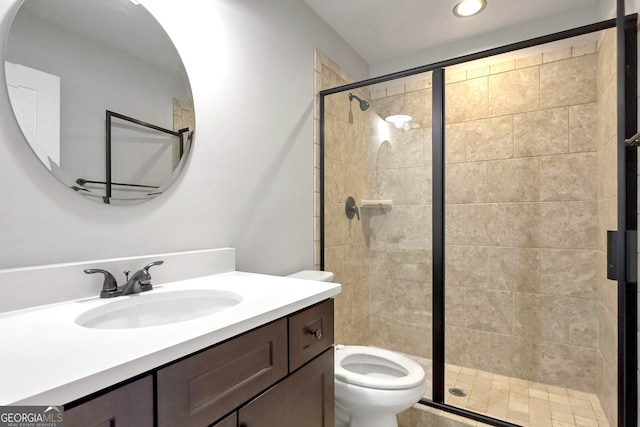 bathroom featuring vanity, toilet, and a shower with shower door