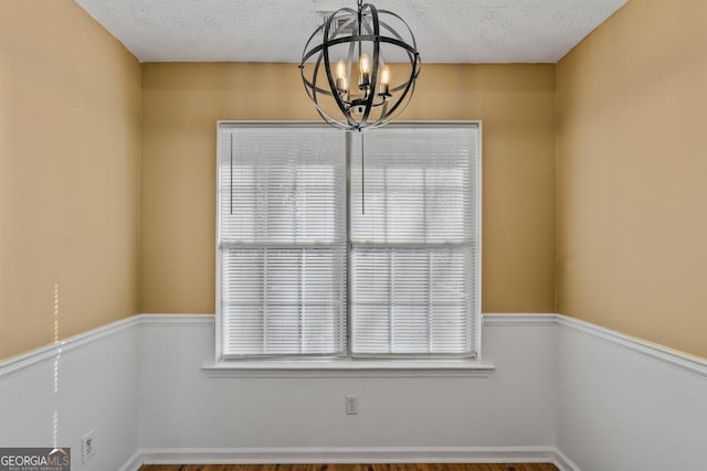 spare room featuring a notable chandelier and a textured ceiling