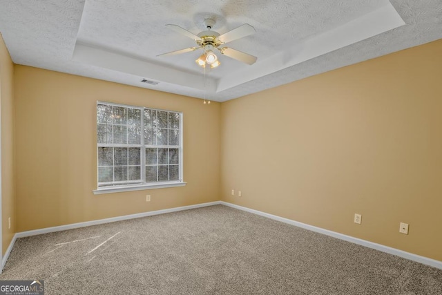 carpeted empty room featuring ceiling fan, a raised ceiling, and a textured ceiling