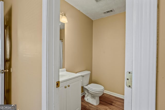 bathroom with vanity, toilet, wood-type flooring, and a textured ceiling