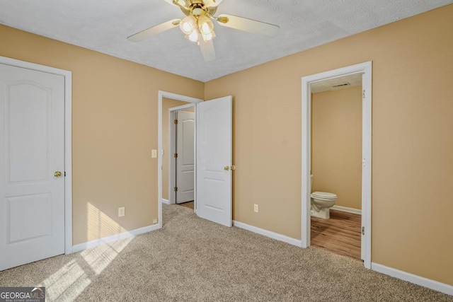 unfurnished bedroom featuring ensuite bathroom, light colored carpet, and ceiling fan