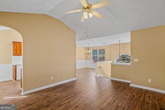 spare room featuring vaulted ceiling, ceiling fan with notable chandelier, hardwood / wood-style floors, and a textured ceiling