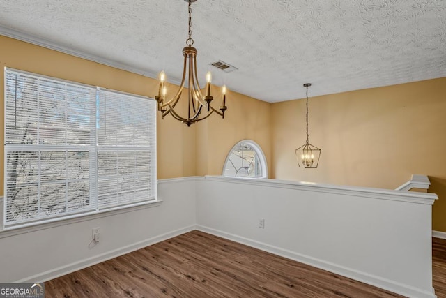 unfurnished dining area featuring dark hardwood / wood-style flooring, a chandelier, and a textured ceiling