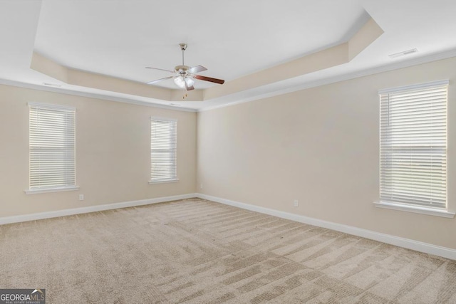 carpeted empty room featuring a tray ceiling and ceiling fan