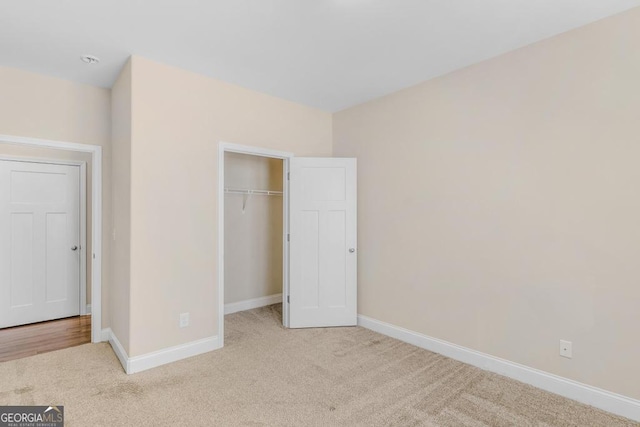 unfurnished bedroom with light colored carpet and a closet