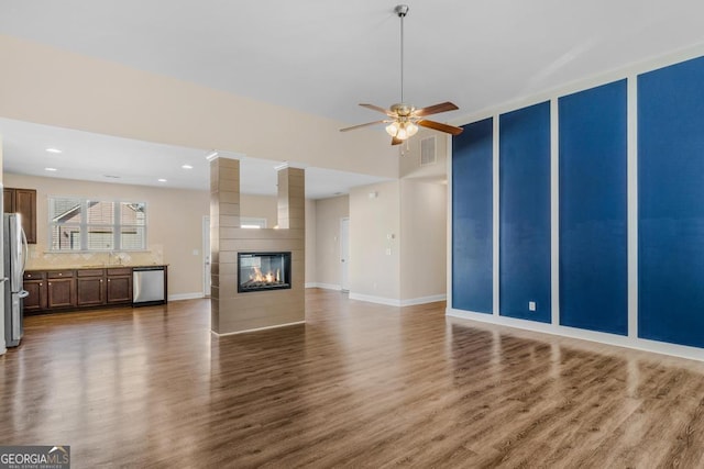 unfurnished living room with ornate columns, wood-type flooring, ceiling fan, and a fireplace