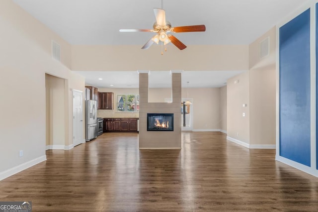 unfurnished living room featuring dark hardwood / wood-style floors, a large fireplace, and ceiling fan