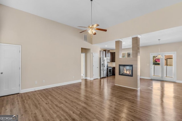 unfurnished living room with ceiling fan, dark hardwood / wood-style floors, a fireplace, and high vaulted ceiling