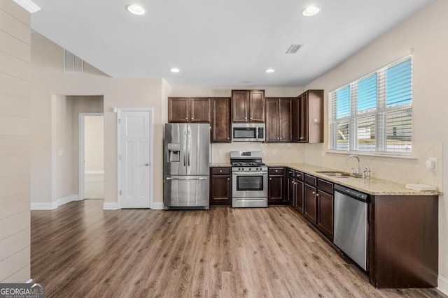 kitchen featuring sink, decorative backsplash, light hardwood / wood-style flooring, and stainless steel appliances