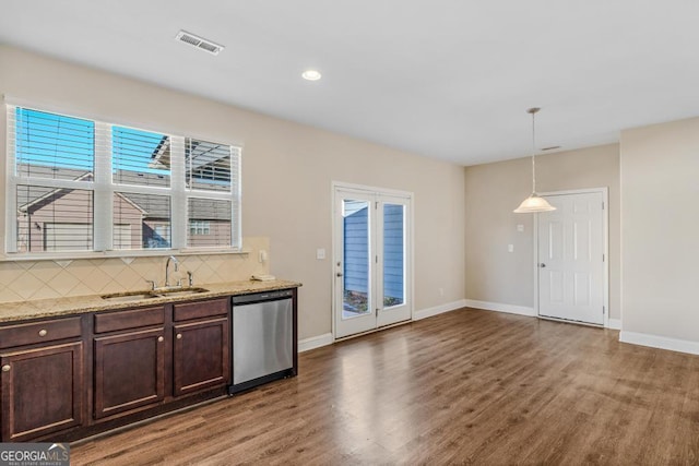 kitchen with sink, dark brown cabinets, light stone counters, decorative light fixtures, and stainless steel dishwasher