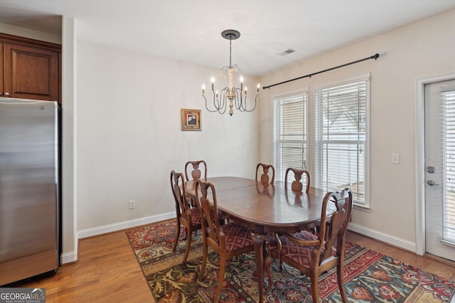 dining area featuring light hardwood / wood-style flooring and a notable chandelier