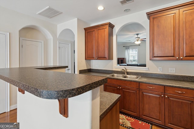 kitchen featuring sink, a breakfast bar area, ceiling fan, a center island, and dark hardwood / wood-style flooring