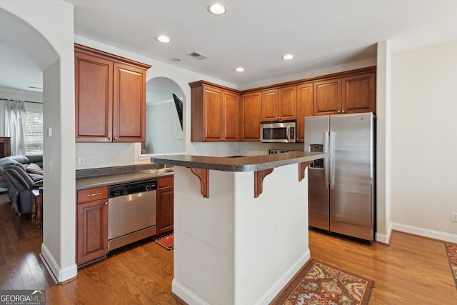 kitchen featuring stainless steel appliances, a kitchen island, a breakfast bar area, and light hardwood / wood-style floors