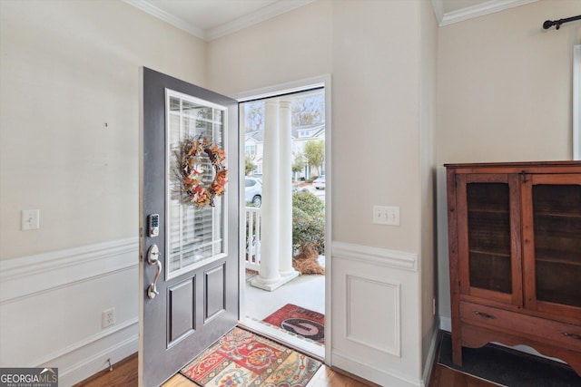 entrance foyer featuring crown molding, light hardwood / wood-style floors, and decorative columns