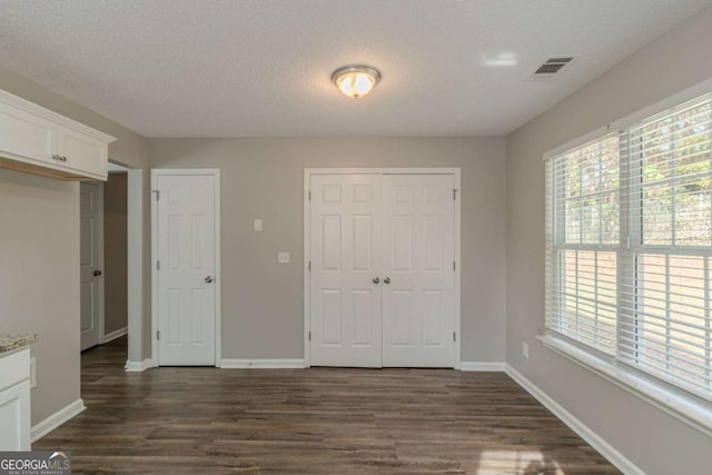 unfurnished bedroom featuring dark hardwood / wood-style floors, two closets, and a textured ceiling