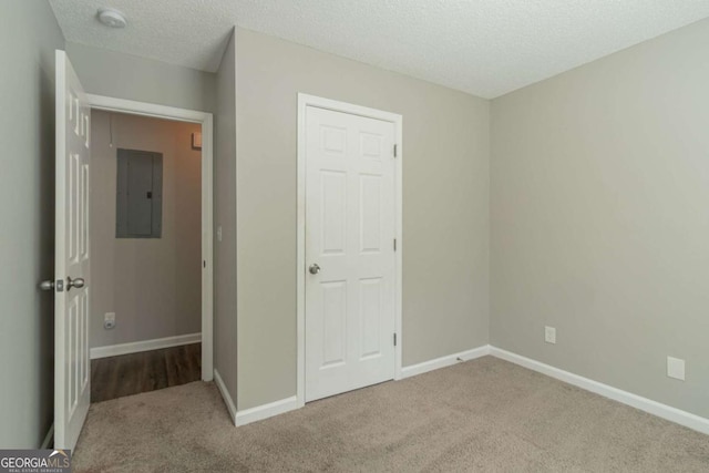 unfurnished bedroom with electric panel, carpet, and a textured ceiling