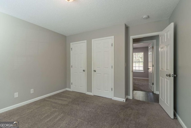 unfurnished bedroom with multiple closets, carpet, and a textured ceiling