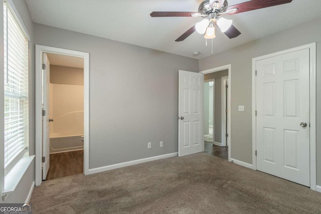 unfurnished bedroom with ceiling fan, connected bathroom, and carpet