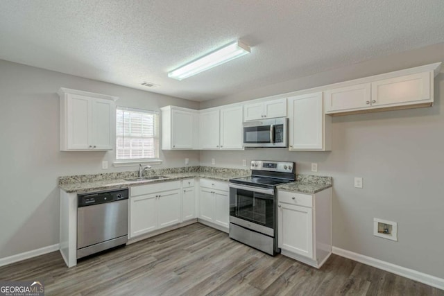 kitchen featuring sink, stainless steel appliances, light hardwood / wood-style floors, and white cabinets