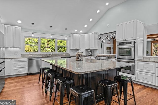 kitchen featuring a breakfast bar area, a center island, white cabinets, and appliances with stainless steel finishes