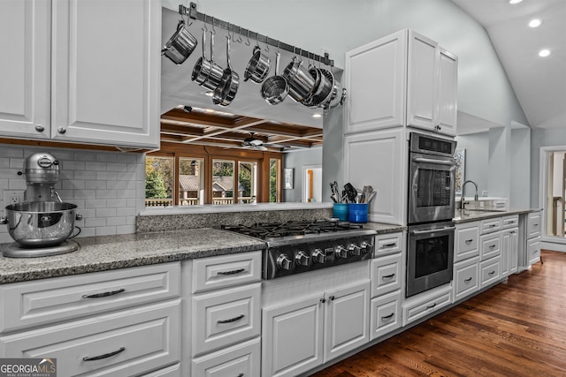 kitchen featuring coffered ceiling, dark hardwood / wood-style floors, white cabinets, stainless steel appliances, and backsplash