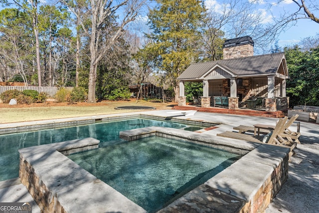 view of pool with a fireplace, a patio area, an outdoor structure, and an in ground hot tub