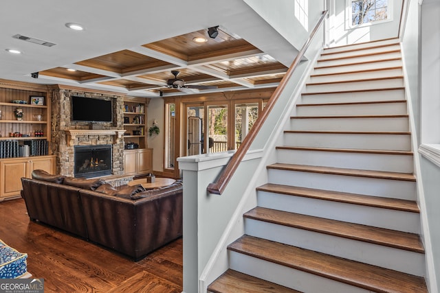 living room featuring a stone fireplace, coffered ceiling, wood ceiling, ceiling fan, and dark wood-type flooring