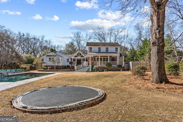 back of house featuring a fenced in pool, a sunroom, and a trampoline