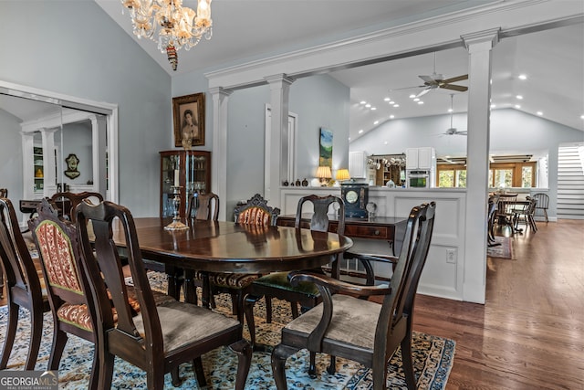 dining area with decorative columns, dark wood-type flooring, ceiling fan with notable chandelier, and high vaulted ceiling