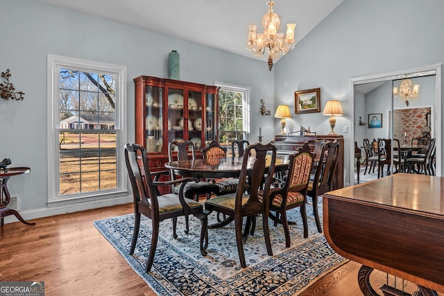 dining area with lofted ceiling, a notable chandelier, and light hardwood / wood-style flooring