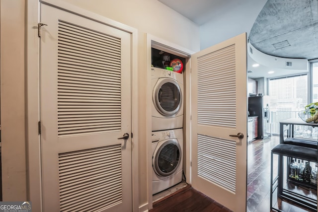 laundry area featuring stacked washer / drying machine and dark wood-type flooring