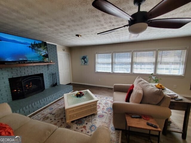 living room featuring hardwood / wood-style flooring, ceiling fan, a wealth of natural light, and a fireplace